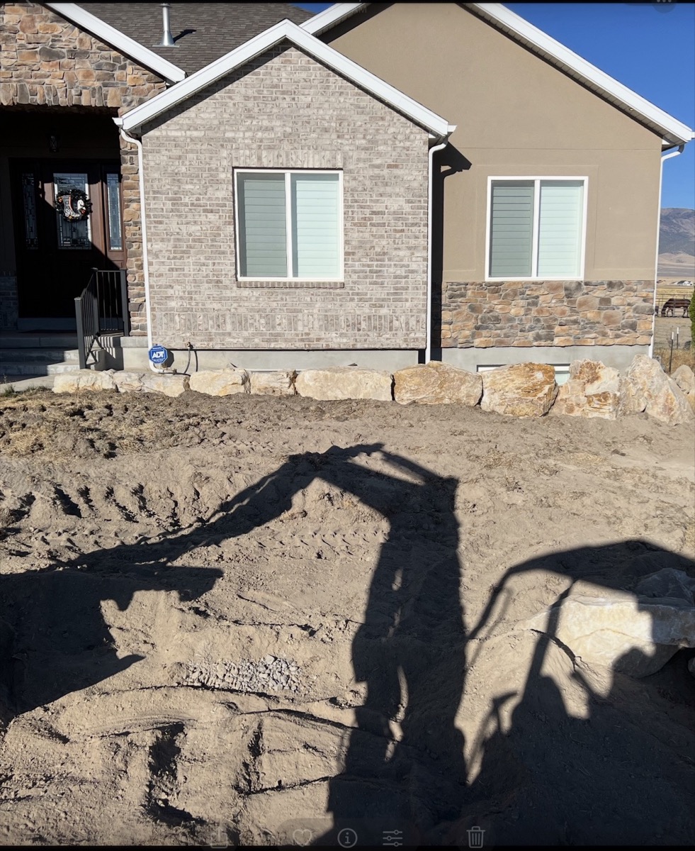 Boulder being placed by excavator for retaining wall