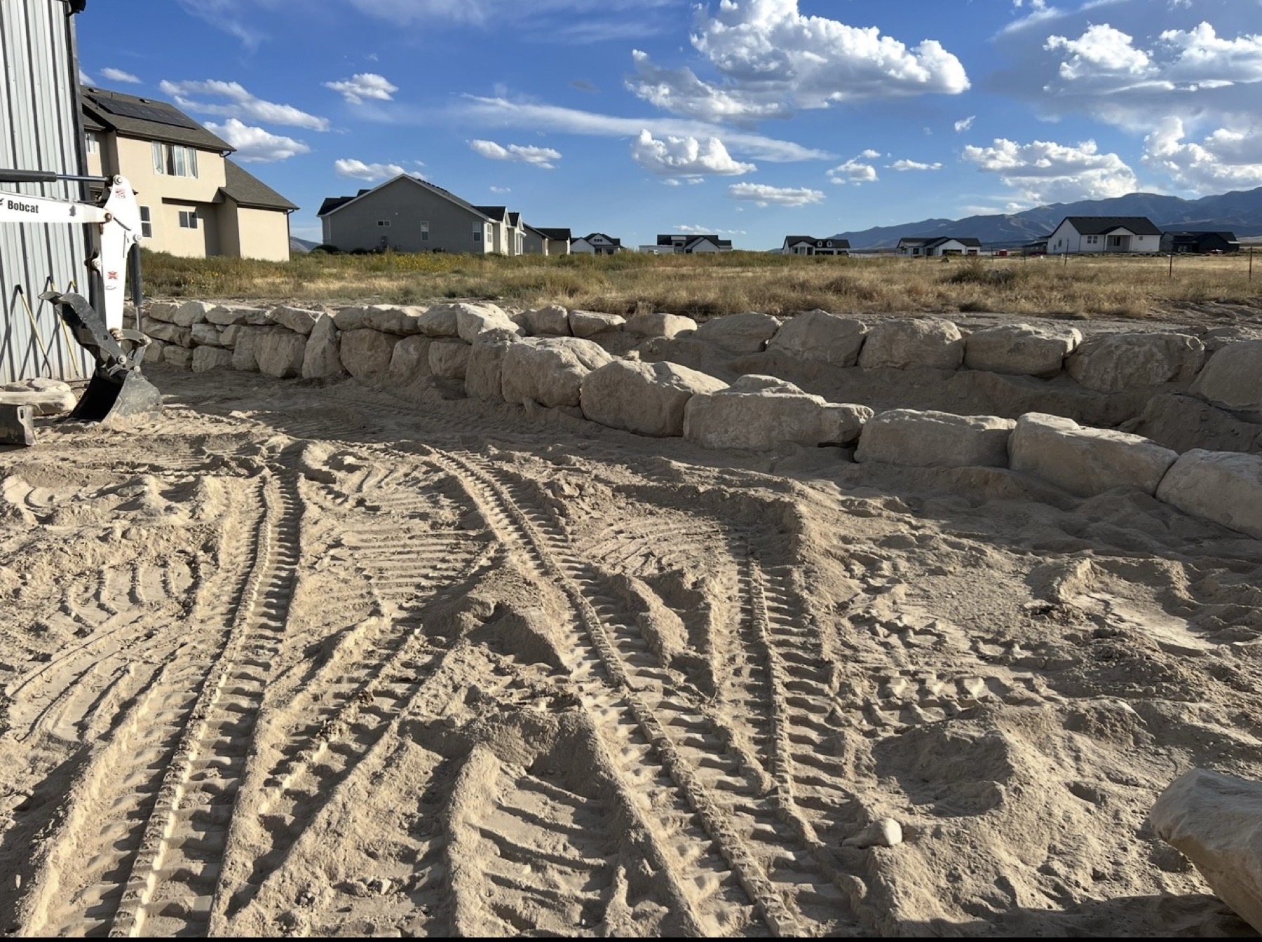Boulder retaining wall under construction with Wasatch mountains
