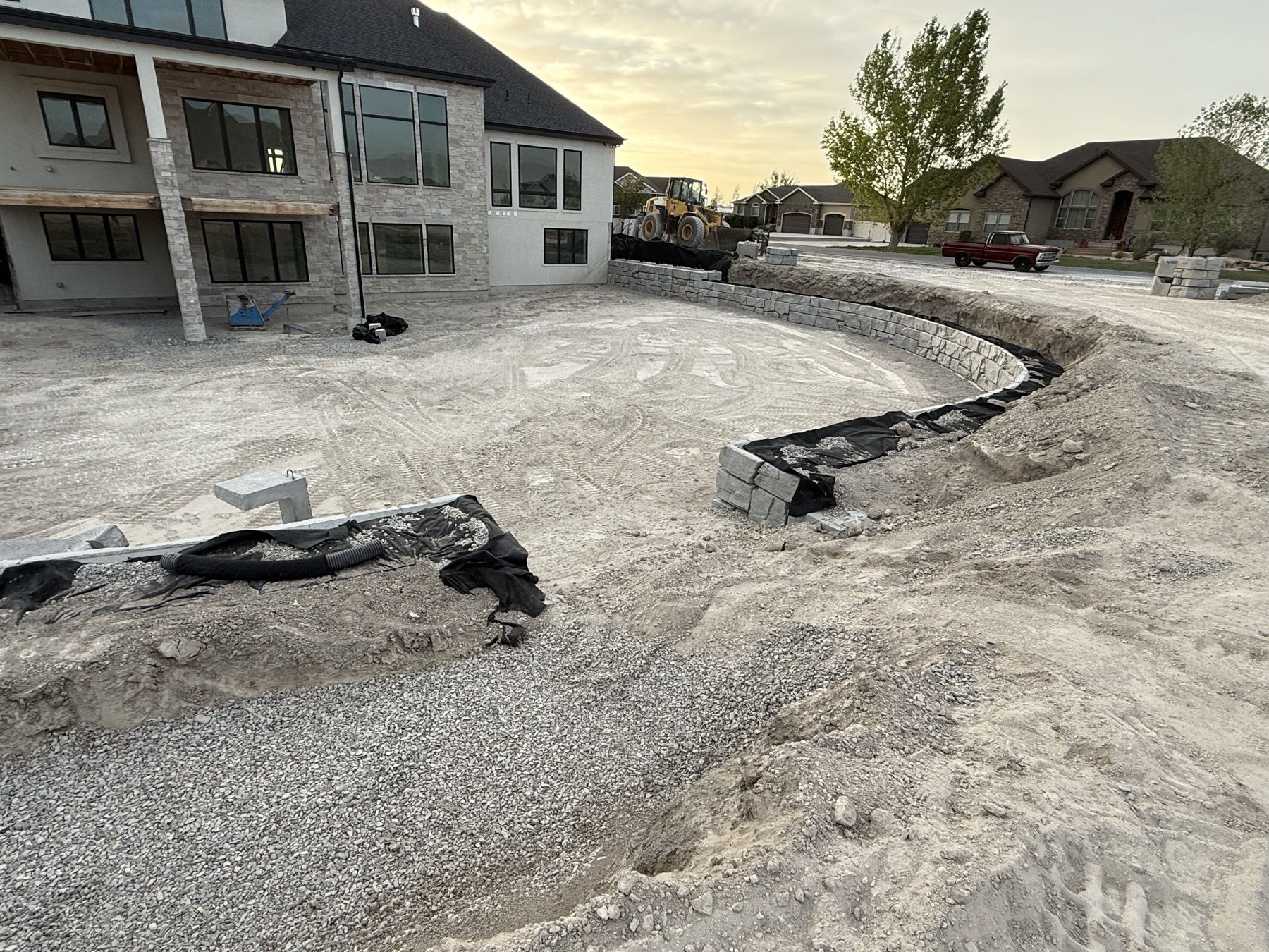 Boulder retaining wall at golden hour with luxury home