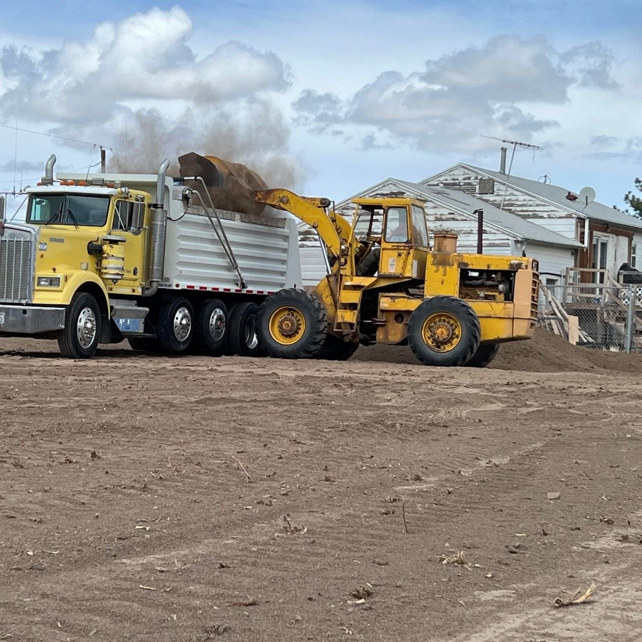 Front loader loading screened dirt into dump truck